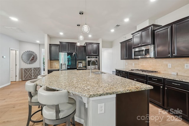 5812 Dinsmore Ln, Belmont, NC 28012 - kitchen with stainless steel appliances, a sink, backsplash, an island with sink, and light stone counters