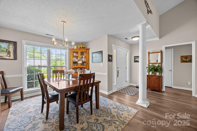 296 Planters Creek Rd, Fletcher, NC 28732 - dining area featuring ornate columns, wood finished floors, a chandelier, a textured ceiling, and baseboards