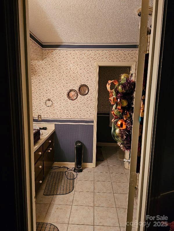100 Boros Lndg, New Bern, NC 28560 - bathroom with wallpapered walls, a textured ceiling, tile patterned flooring, and a wainscoted wall
