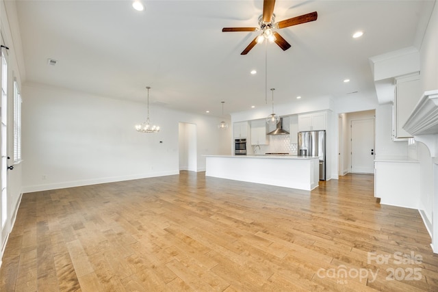 unfurnished living room featuring ceiling fan, a chandelier, recessed lighting, light wood-style floors, and baseboards