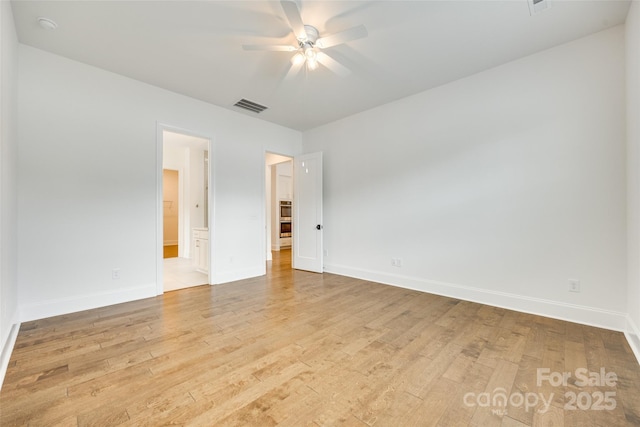 unfurnished room with ceiling fan, light wood finished floors, and baseboards