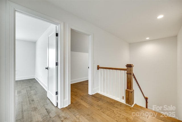 hall with an upstairs landing, wood finished floors, recessed lighting, and baseboards