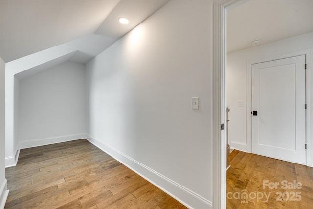 additional living space featuring light wood-style floors, lofted ceiling, baseboards, and recessed lighting