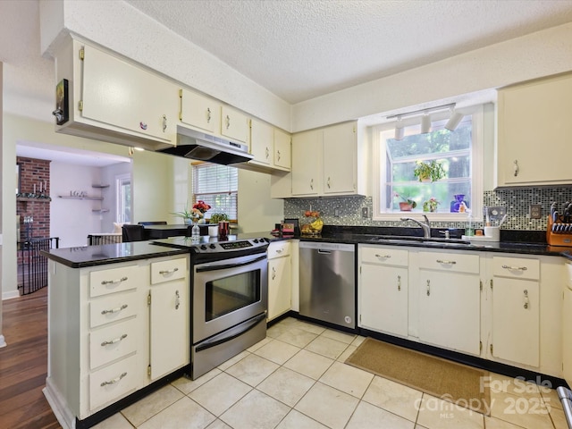 11718 Battery Pl, Charlotte, NC 28273 - kitchen with stainless steel appliances, under cabinet range hood, a peninsula, a sink, and dark countertops