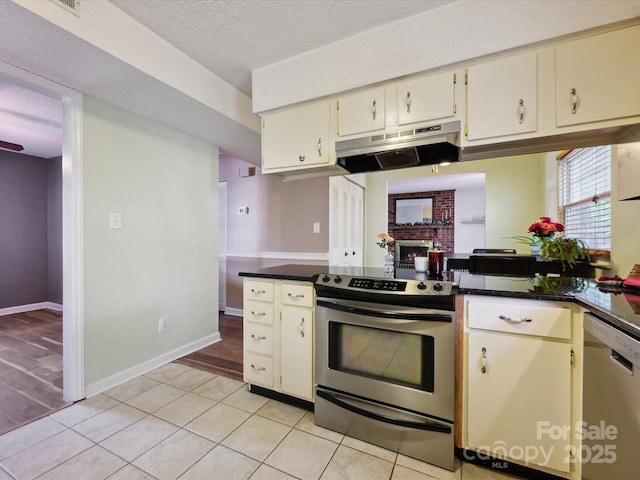 11718 Battery Pl, Charlotte, NC 28273 - kitchen featuring stainless steel appliances, under cabinet range hood, dark countertops, a brick fireplace, and a textured ceiling