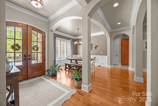 104 Golden Bell Ct, Mooresville, NC 28117 - entryway with arched walkways, light wood-style floors, a chandelier, crown molding, and french doors