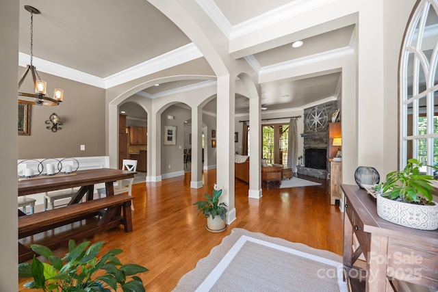 104 Golden Bell Ct, Mooresville, NC 28117 - entrance foyer with ornamental molding, a fireplace, a chandelier, light wood-style flooring, and arched walkways