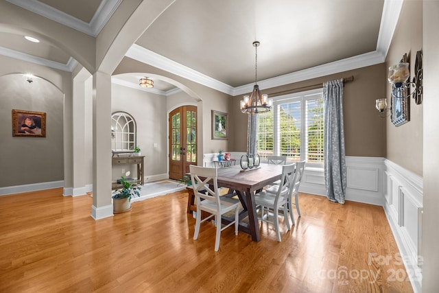 104 Golden Bell Ct, Mooresville, NC 28117 - dining area featuring arched walkways, a chandelier, french doors, light wood-type flooring, and wainscoting