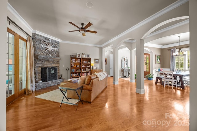 104 Golden Bell Ct, Mooresville, NC 28117 - living area featuring arched walkways, ceiling fan, a fireplace, light wood finished floors, and ornamental molding