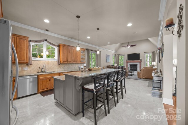 104 Golden Bell Ct, Mooresville, NC 28117 - kitchen with appliances with stainless steel finishes, a sink, brown cabinets, a center island, and a ceiling fan