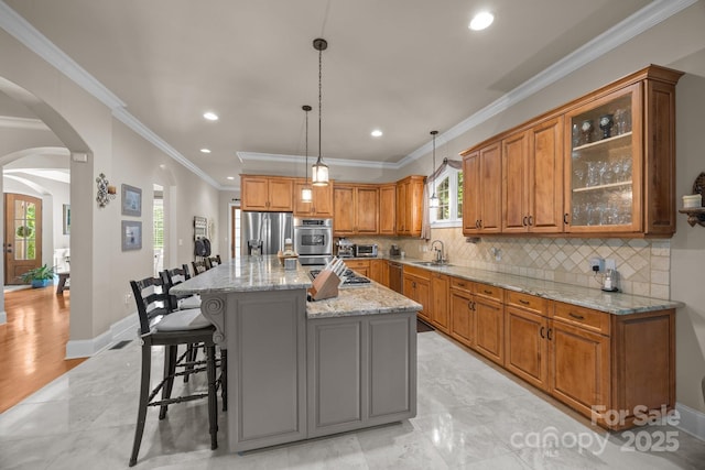 104 Golden Bell Ct, Mooresville, NC 28117 - kitchen featuring a sink, stainless steel appliances, brown cabinetry, arched walkways, and ornamental molding