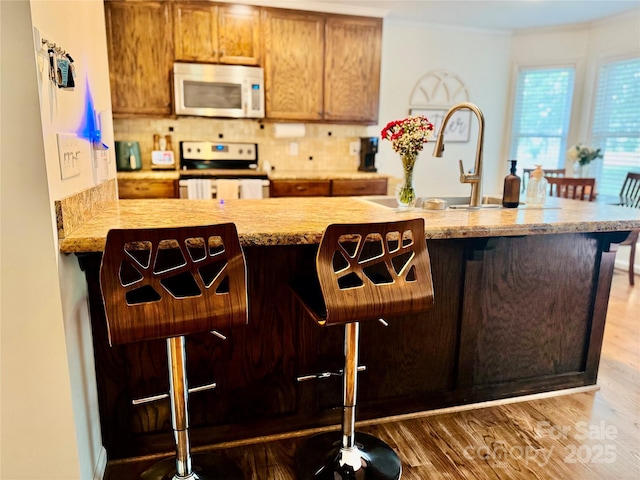 312 Shady Ln, Lincolnton, NC 28092 - kitchen with white microwave, stainless steel electric stove, wood finished floors, backsplash, and a kitchen bar
