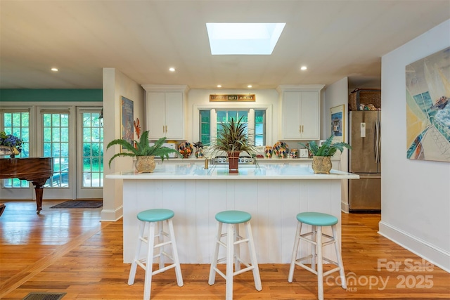 212 Vance Ave, Black Mountain, NC 28711 - kitchen featuring freestanding refrigerator, a skylight, light countertops, white cabinets, and recessed lighting