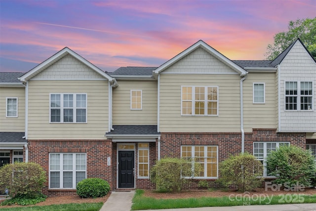townhome / multi-family property with brick siding and a shingled roof