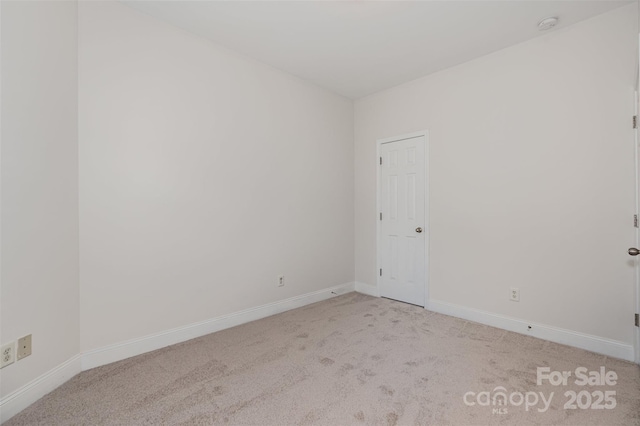 carpeted spare room featuring baseboards and a smoke detector