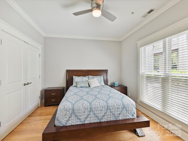 bedroom with light wood-style floors, ornamental molding, and a ceiling fan