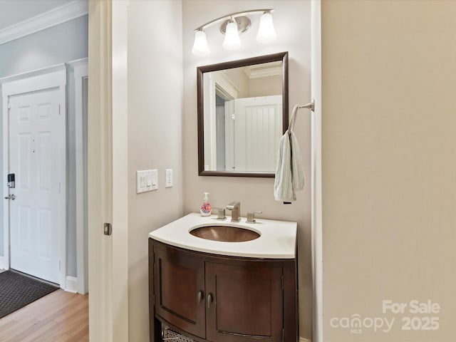 bathroom featuring crown molding, wood finished floors, vanity, and baseboards
