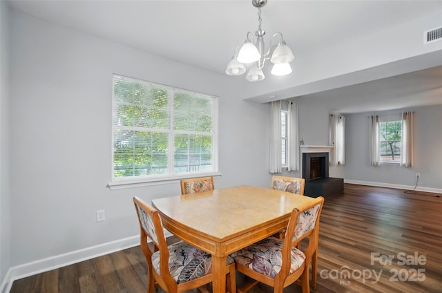 8014 Sherington Way, Charlotte, NC 28227 - dining area featuring a chandelier, a fireplace with raised hearth, dark wood finished floors, and baseboards