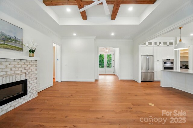 9311 Simpson Rd, Waxhaw, NC 28173 - unfurnished living room featuring light wood-style floors, beam ceiling, recessed lighting, a brick fireplace, and coffered ceiling