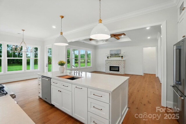 9311 Simpson Rd, Waxhaw, NC 28173 - kitchen with appliances with stainless steel finishes, a sink, light countertops, a glass covered fireplace, and white cabinetry