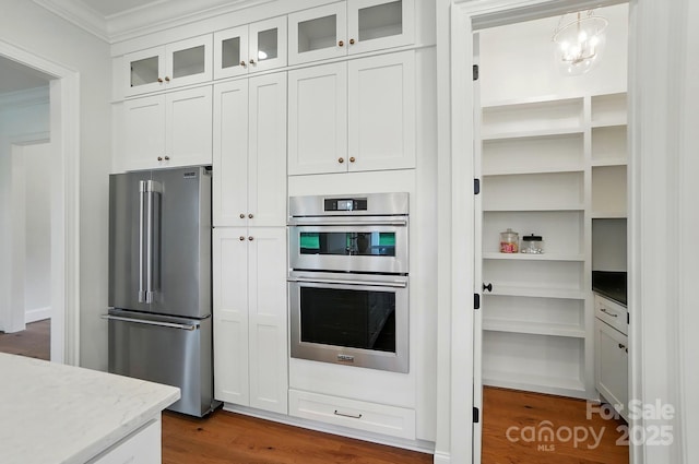 9311 Simpson Rd, Waxhaw, NC 28173 - kitchen with appliances with stainless steel finishes, ornamental molding, white cabinetry, light stone countertops, and dark wood-style flooring