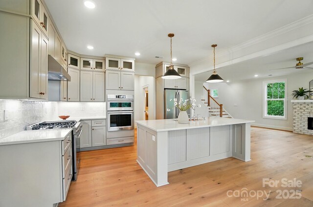 9315 Simpson Rd, Waxhaw, NC 28173 - kitchen featuring appliances with stainless steel finishes, under cabinet range hood, ornamental molding, decorative backsplash, and a center island
