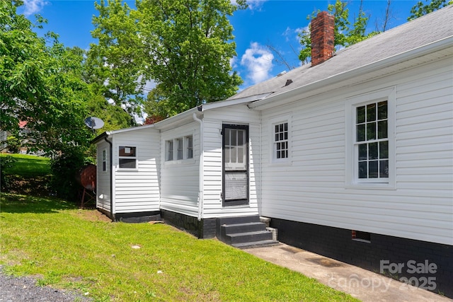back of house with entry steps, a yard, a chimney, and crawl space