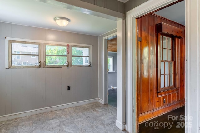 empty room featuring baseboards and wood walls