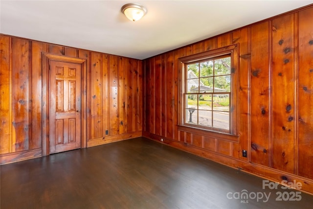 spare room featuring dark wood-type flooring and wooden walls
