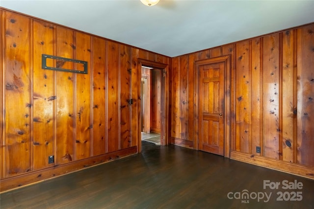 unfurnished room with wood walls and wood finished floors