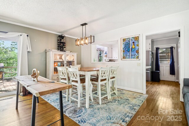 334 Lakeview Cir, Lugoff, SC 29078 - dining area with a chandelier, ornamental molding, wood finished floors, a textured ceiling, and baseboards