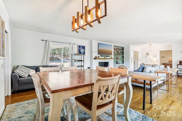 334 Lakeview Cir, Lugoff, SC 29078 - dining room featuring a textured ceiling, a fireplace, light wood-style floors, and a chandelier