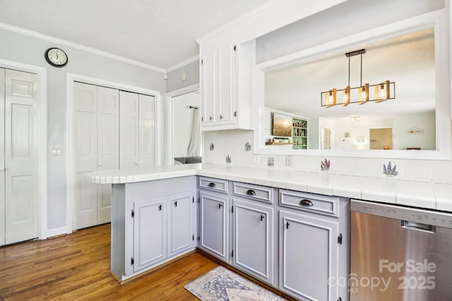 334 Lakeview Cir, Lugoff, SC 29078 - kitchen with stainless steel dishwasher, a peninsula, crown molding, wood finished floors, and tile counters