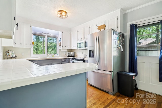 334 Lakeview Cir, Lugoff, SC 29078 - kitchen featuring appliances with stainless steel finishes, tile countertops, a peninsula, a sink, and white cabinets