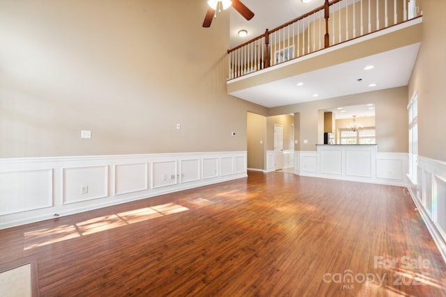 165 N Arcadian Way, Mooresville, NC 28117 - unfurnished living room with ceiling fan, a chandelier, a decorative wall, wood finished floors, and a wainscoted wall
