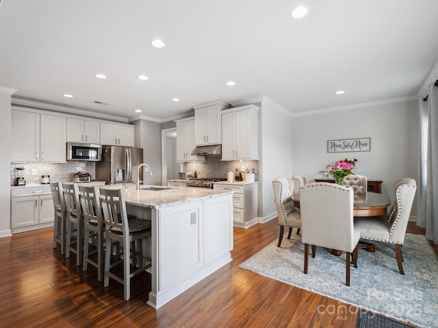 2178 Stone Pile Dr SW, Concord, NC 28025 - kitchen featuring stainless steel appliances, crown molding, under cabinet range hood, a sink, and an island with sink