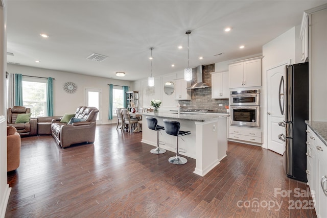 1033 Dorsey Dr, Fort Mill, SC 29715 - kitchen featuring stainless steel appliances, wall chimney exhaust hood, open floor plan, a breakfast bar, and dark wood-style floors