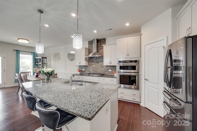 1033 Dorsey Dr, Fort Mill, SC 29715 - kitchen with appliances with stainless steel finishes, a sink, wall chimney exhaust hood, light stone counters, and an island with sink