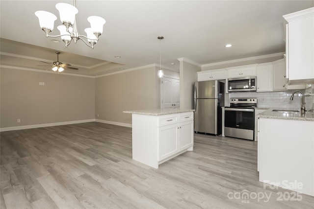 kitchen with appliances with stainless steel finishes, a sink, light wood finished floors, baseboards, and ornamental molding