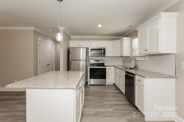 kitchen featuring stainless steel appliances, a sink, light wood-style floors, a kitchen island, and white cabinets