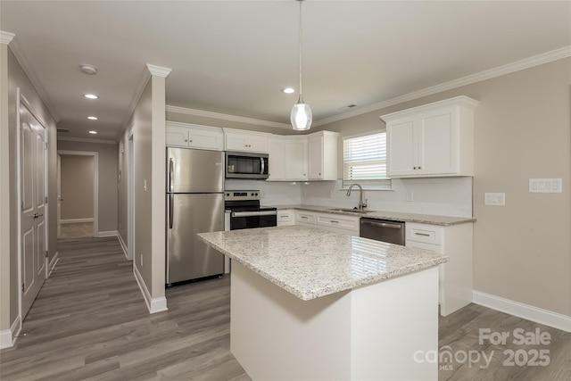 kitchen with appliances with stainless steel finishes, a sink, crown molding, baseboards, and wood finished floors