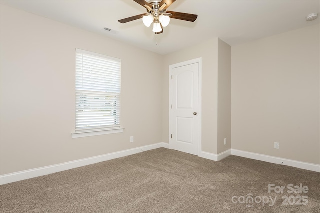 spare room with carpet floors, a ceiling fan, and baseboards