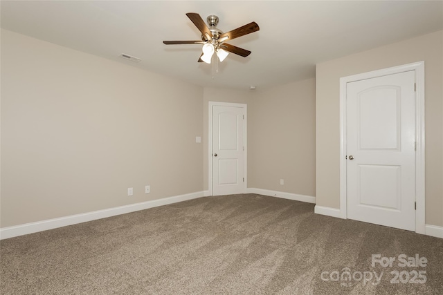 carpeted spare room featuring ceiling fan and baseboards