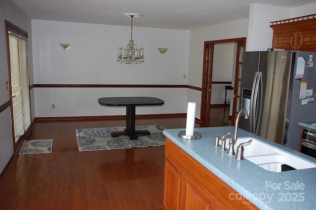 kitchen featuring stainless steel fridge, a sink, dark wood-style floors, and a chandelier