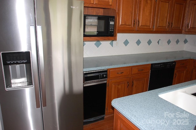 kitchen with black appliances, brown cabinets, tasteful backsplash, and wood finished floors