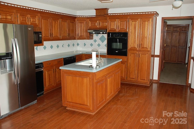 kitchen featuring black appliances, a sink, brown cabinetry, and tasteful backsplash