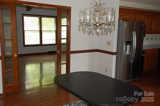 dining space with dark wood-style flooring and a chandelier