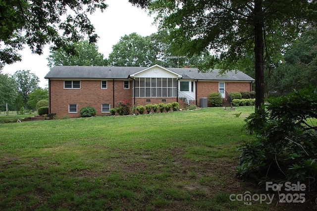 rear view of property featuring a sunroom, cooling unit, brick siding, and entry steps