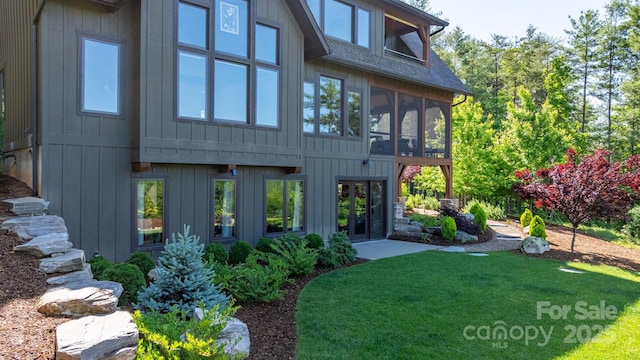 rear view of property featuring a sunroom, a yard, and a shingled roof