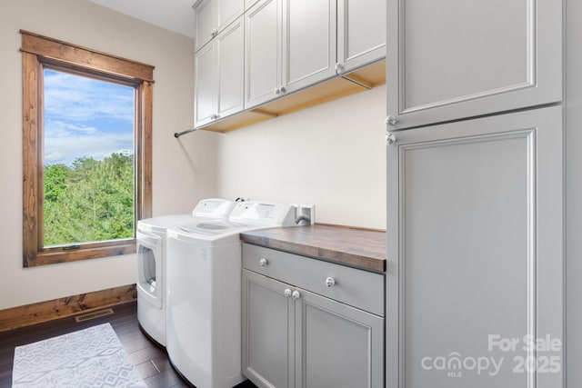 laundry area featuring cabinet space, healthy amount of natural light, independent washer and dryer, and dark wood-style flooring